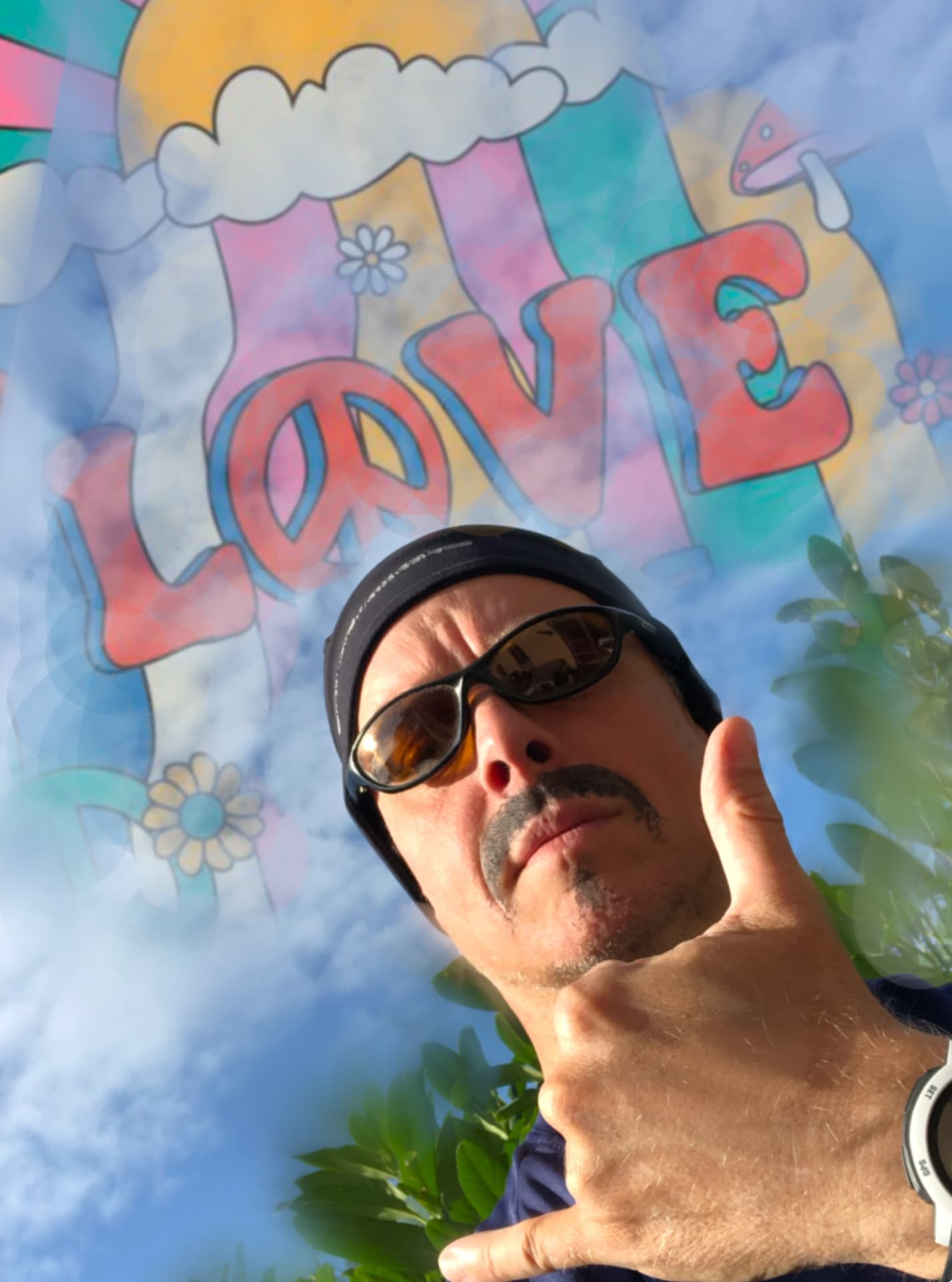 Chris Big MacDonald foran en LOVE-mur med solbriller og pandebånd